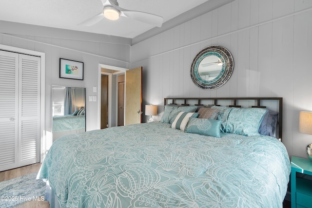 bedroom featuring ceiling fan, hardwood / wood-style floors, lofted ceiling, wooden walls, and a closet