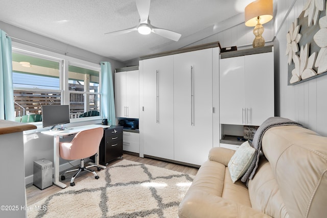 office area with ceiling fan, light wood-type flooring, and a textured ceiling