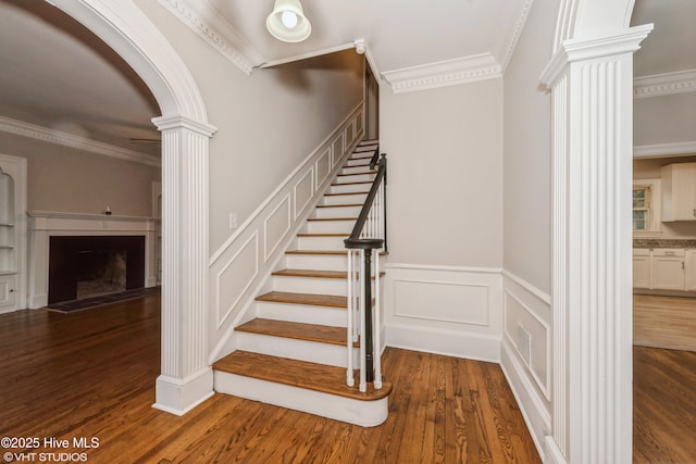 stairs featuring ornate columns, hardwood / wood-style flooring, and ornamental molding