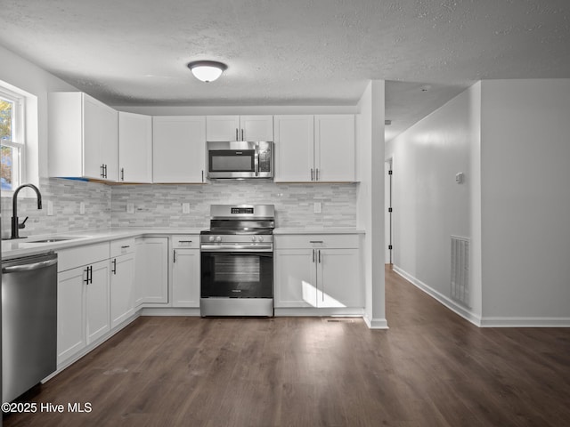 kitchen with sink, white cabinetry, backsplash, dark hardwood / wood-style flooring, and appliances with stainless steel finishes