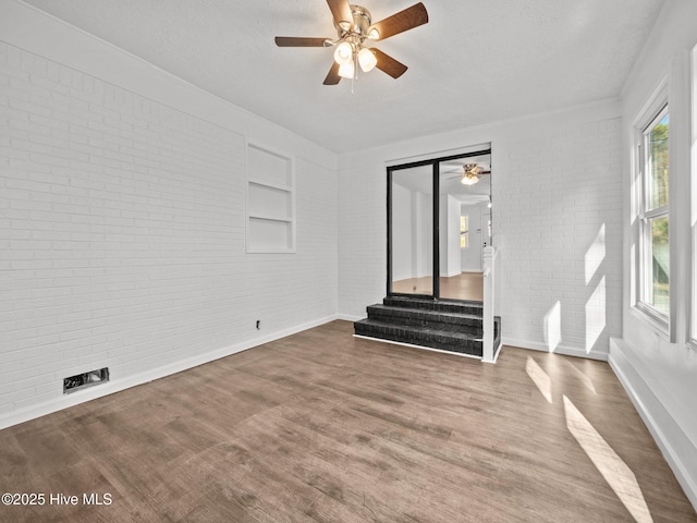 unfurnished living room with brick wall and a textured ceiling