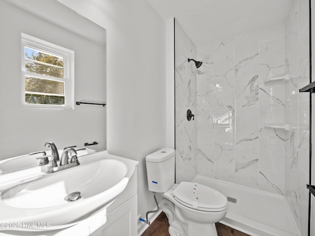 bathroom featuring toilet, tiled shower, vanity, and hardwood / wood-style floors