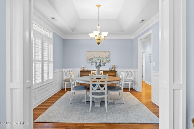 dining space featuring hardwood / wood-style floors, a tray ceiling, and a chandelier