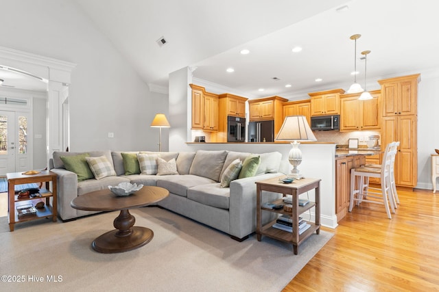 living room with lofted ceiling, crown molding, decorative columns, and light wood-type flooring