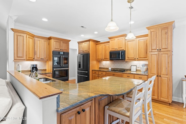 kitchen with a kitchen bar, sink, decorative light fixtures, kitchen peninsula, and black appliances