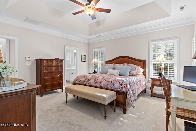 bedroom featuring connected bathroom, crown molding, light carpet, a tray ceiling, and ceiling fan