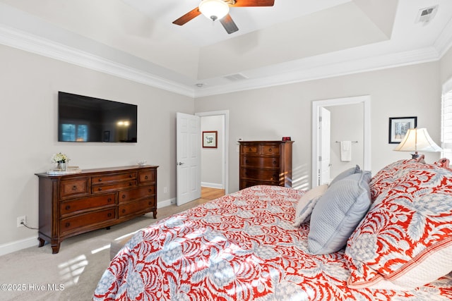 bedroom with a tray ceiling, ornamental molding, light colored carpet, and ceiling fan