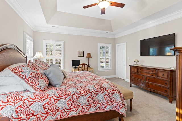 carpeted bedroom with a tray ceiling, ornamental molding, and ceiling fan