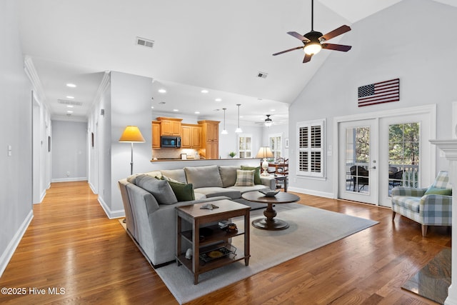 living room with a wealth of natural light, light hardwood / wood-style flooring, and high vaulted ceiling