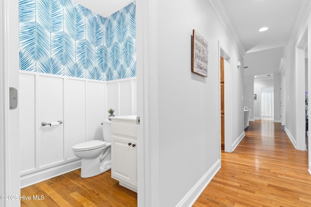 bathroom featuring wood-type flooring, ornamental molding, and toilet