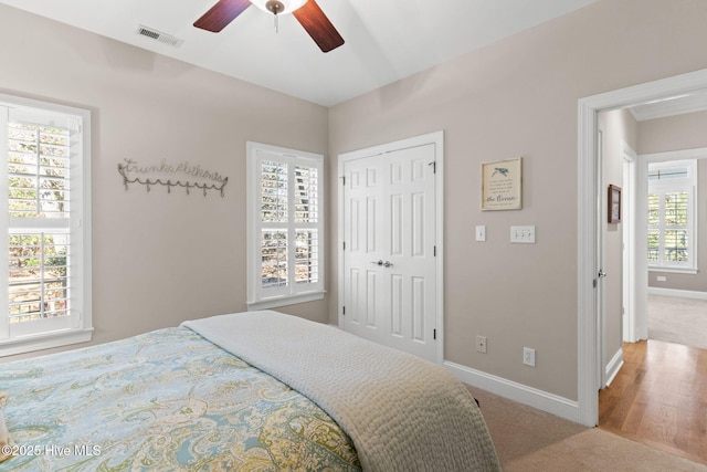 bedroom with light colored carpet, ceiling fan, and a closet