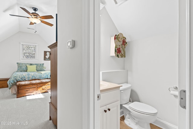 bathroom featuring ceiling fan, lofted ceiling, toilet, and vanity