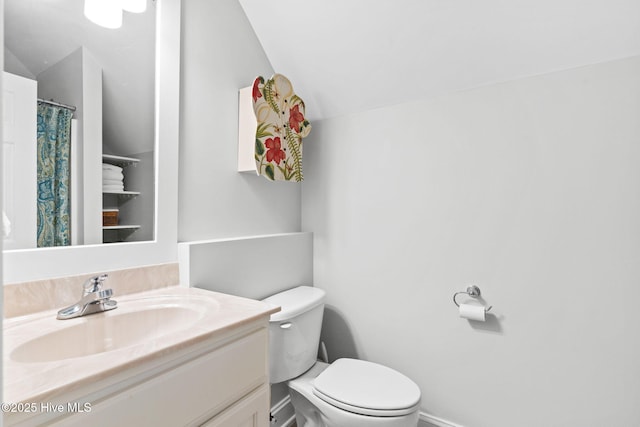 bathroom with lofted ceiling, vanity, and toilet