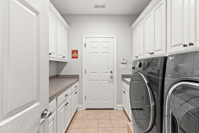 laundry room featuring light tile patterned floors, washing machine and dryer, and cabinets