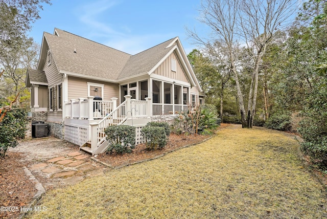 rear view of property featuring a sunroom, a lawn, a deck, and central air condition unit