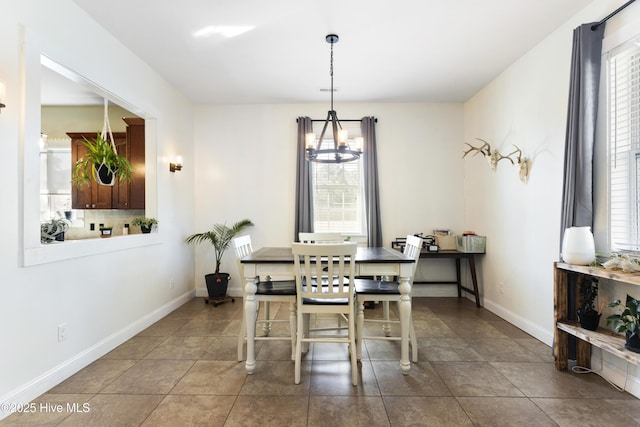 dining area with a wealth of natural light, dark tile patterned floors, and a notable chandelier