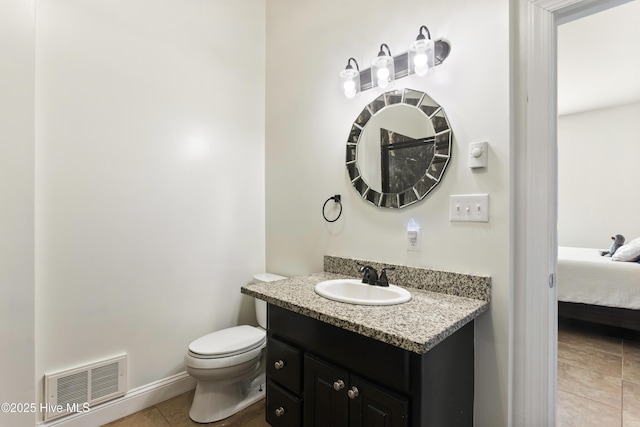 bathroom with toilet, vanity, and tile patterned floors