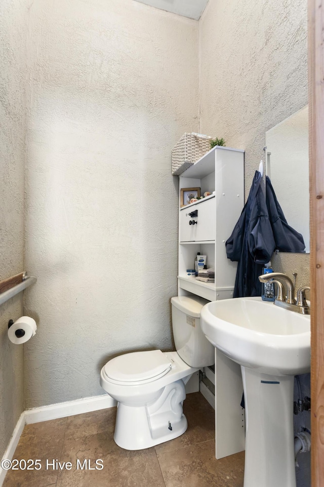 bathroom featuring toilet, tile patterned flooring, and sink