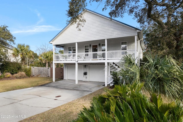 coastal home featuring covered porch, a front yard, and a garage