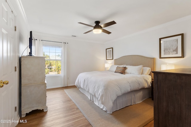 bedroom with ornamental molding, ceiling fan, and light hardwood / wood-style floors