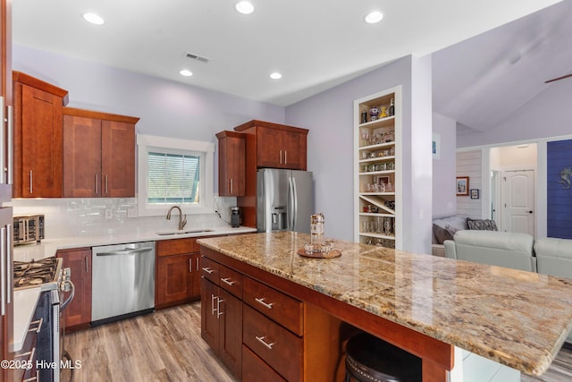 kitchen with decorative backsplash, sink, built in features, stainless steel appliances, and light stone counters