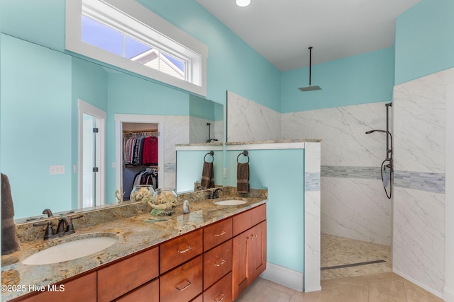 bathroom with tiled shower, vanity, and tile patterned flooring