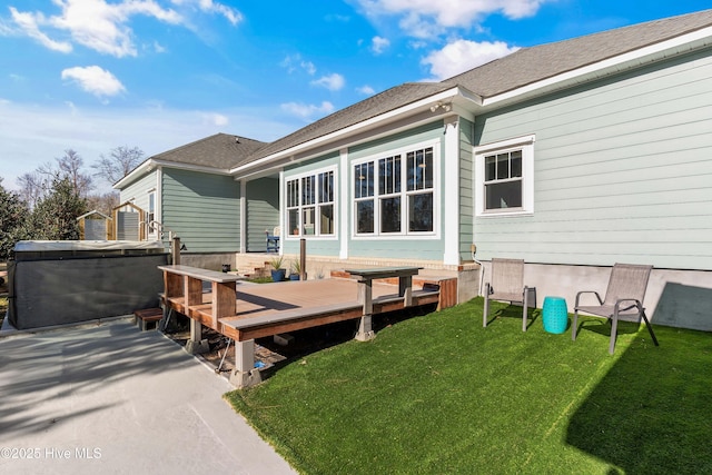 back of house featuring a hot tub, a deck, and a yard