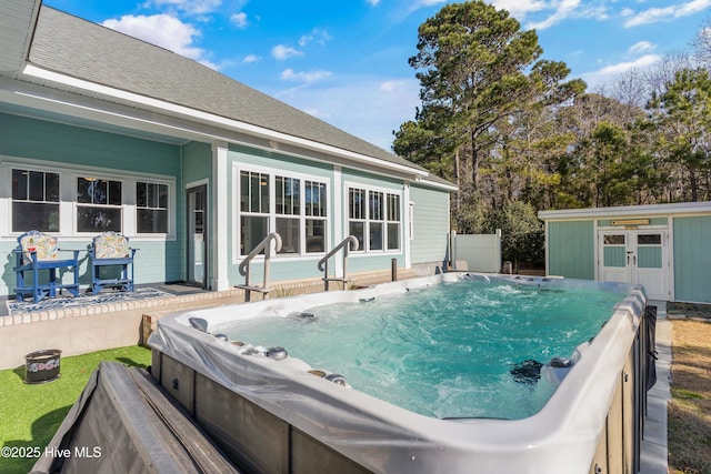 view of swimming pool with a hot tub and an outbuilding