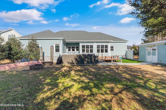 back of house featuring an outdoor fire pit, a hot tub, and a yard