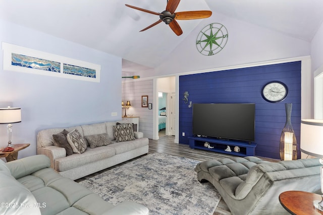 living room with ceiling fan, hardwood / wood-style floors, high vaulted ceiling, and wood walls