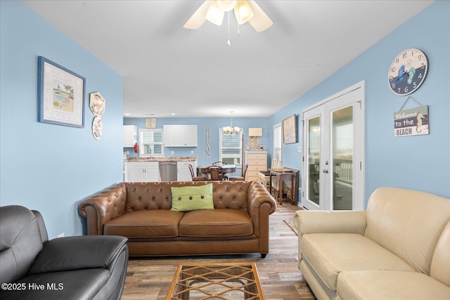 living room featuring hardwood / wood-style flooring, ceiling fan with notable chandelier, and french doors