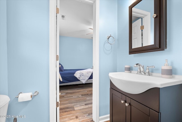 bathroom featuring hardwood / wood-style flooring, vanity, ceiling fan, and toilet