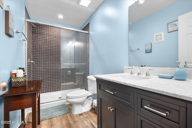 bathroom with toilet, vanity, a shower with shower door, and hardwood / wood-style flooring