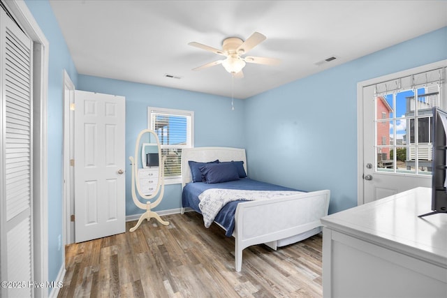 bedroom featuring multiple windows, hardwood / wood-style flooring, and ceiling fan