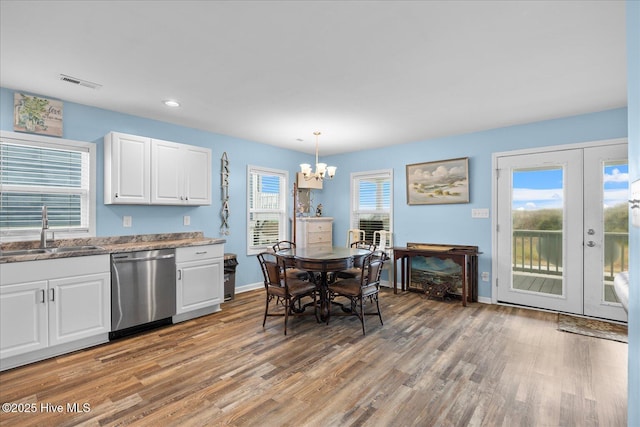 kitchen with sink, stainless steel dishwasher, a notable chandelier, pendant lighting, and white cabinets