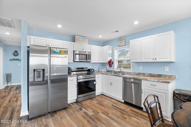 kitchen with white cabinetry, sink, hardwood / wood-style flooring, and appliances with stainless steel finishes