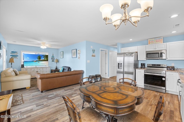 dining space featuring ceiling fan with notable chandelier and light hardwood / wood-style floors