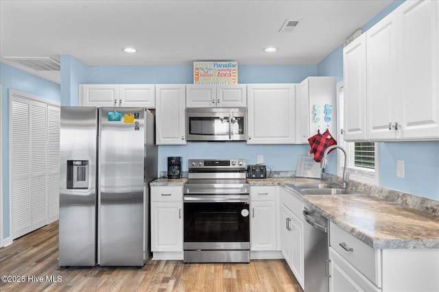 kitchen with light hardwood / wood-style flooring, stainless steel appliances, white cabinetry, and sink