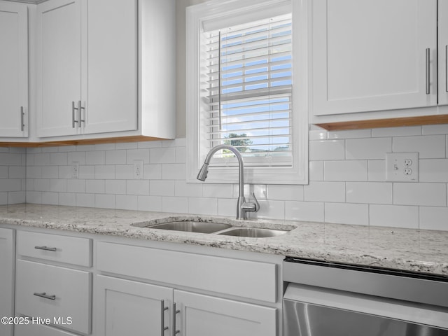 kitchen featuring dishwasher, white cabinets, tasteful backsplash, and a sink