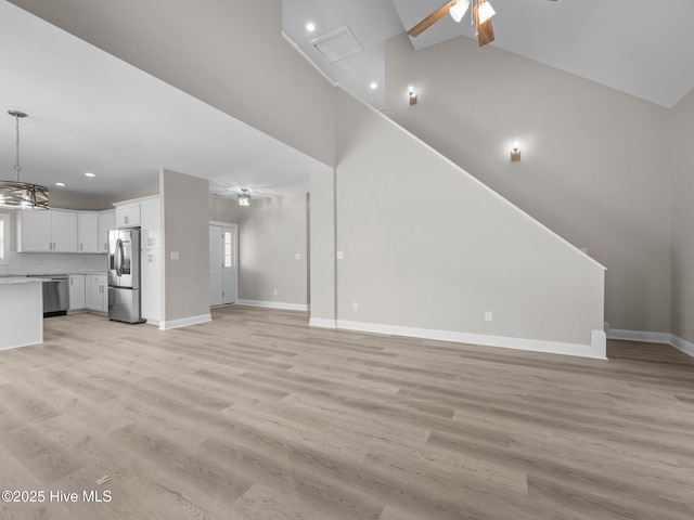 unfurnished living room with recessed lighting, baseboards, high vaulted ceiling, and ceiling fan with notable chandelier