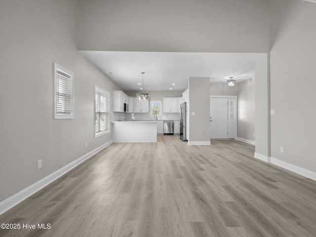 unfurnished living room with baseboards, a notable chandelier, light wood-style floors, and recessed lighting