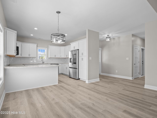 kitchen with a peninsula, recessed lighting, an inviting chandelier, decorative backsplash, and appliances with stainless steel finishes