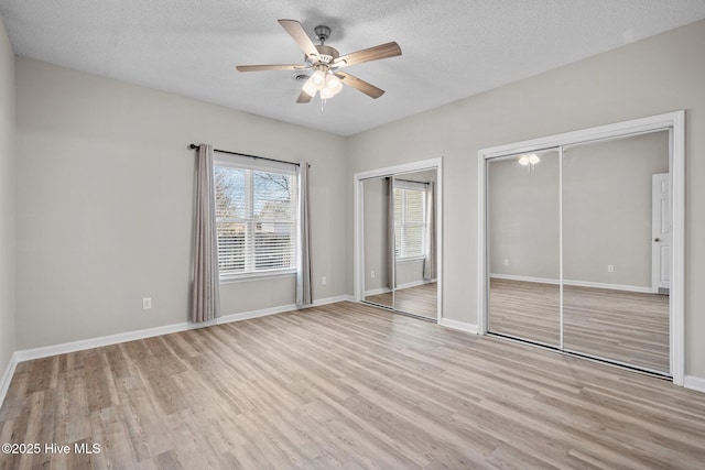 2214 Splitbrook Ct, Wilmington, NC 28411 - unfurnished bedroom featuring two closets, light wood-type flooring, a textured ceiling, baseboards, and ceiling fan
