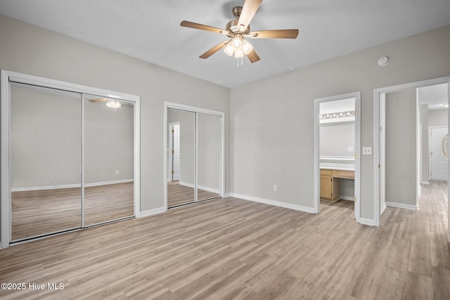 2214 Splitbrook Ct, Wilmington, NC 28411 - unfurnished bedroom with two closets, light wood-style floors, baseboards, ensuite bathroom, and a textured ceiling