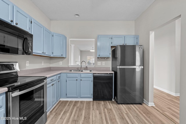 2214 Splitbrook Ct, Wilmington, NC 28411 - kitchen with black appliances, a sink, blue cabinetry, light wood-type flooring, and a textured ceiling