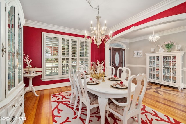 dining area with an inviting chandelier, light hardwood / wood-style flooring, and ornamental molding