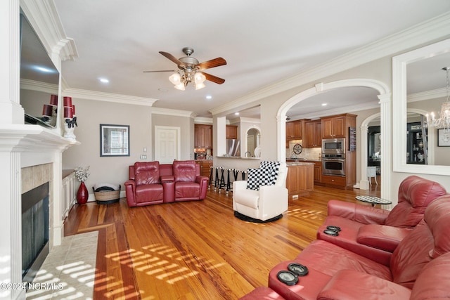 living room featuring crown molding, ceiling fan, a fireplace, and light hardwood / wood-style floors