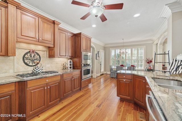 kitchen with sink, light stone counters, crown molding, light wood-type flooring, and appliances with stainless steel finishes