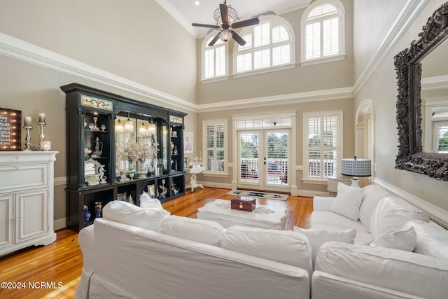 living room with crown molding, french doors, ceiling fan, and light wood-type flooring