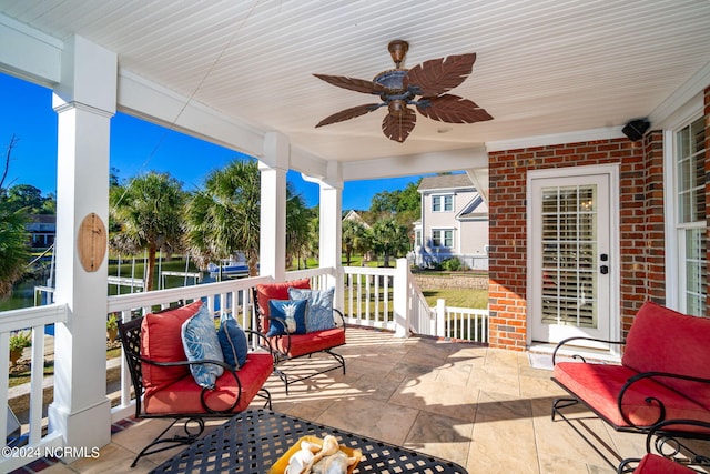 view of patio featuring a porch, ceiling fan, and a water view